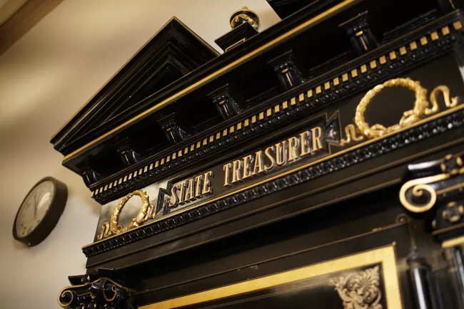 Black vault with the words state treasurer on it and a clock next to it on the wall